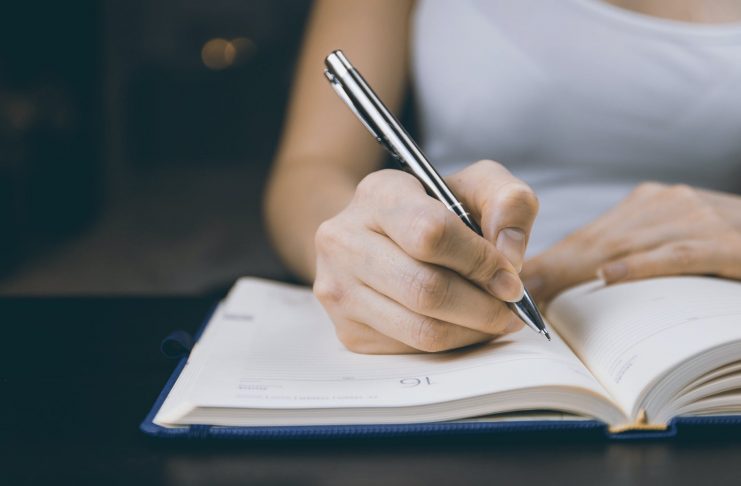 photo of person writing on notebook